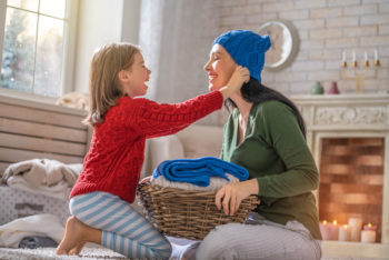 Winter portrait of happy loving family wearing knitted sweaters. Mother and child girl having fun, playing and laughing at home.