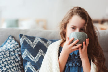 child girl wearing blanket and drinking hot tea 