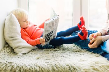 Toddler laying down and reading book in Smyrna, TN