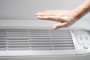 A person feels their air conditioning unit to see whether it's cool
