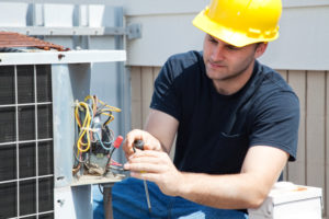 Young repairman fixing an industrial air conditioning compressor