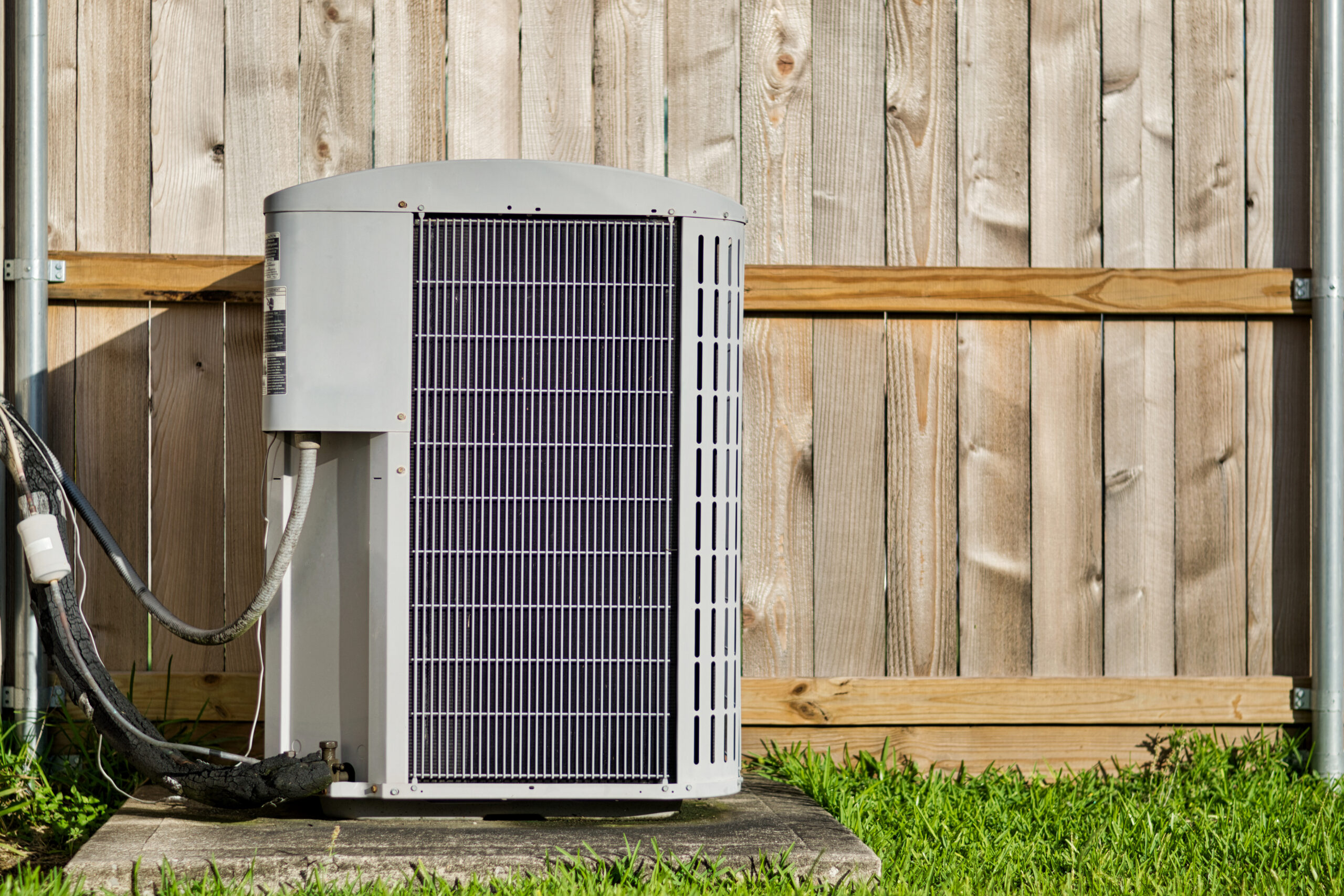 Central air unit maintained by Parkers Heating & Cooling in a backyard with a wooden fence in TN.