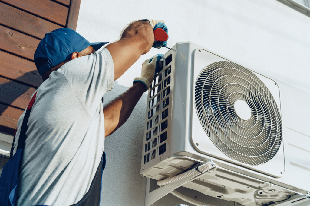 A repairman works on the outside of an AC unit