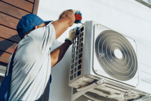 A repairman works on the outside of an AC unit 