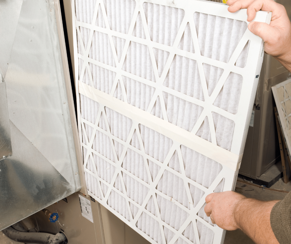 A person replaces a filter in a furnace  