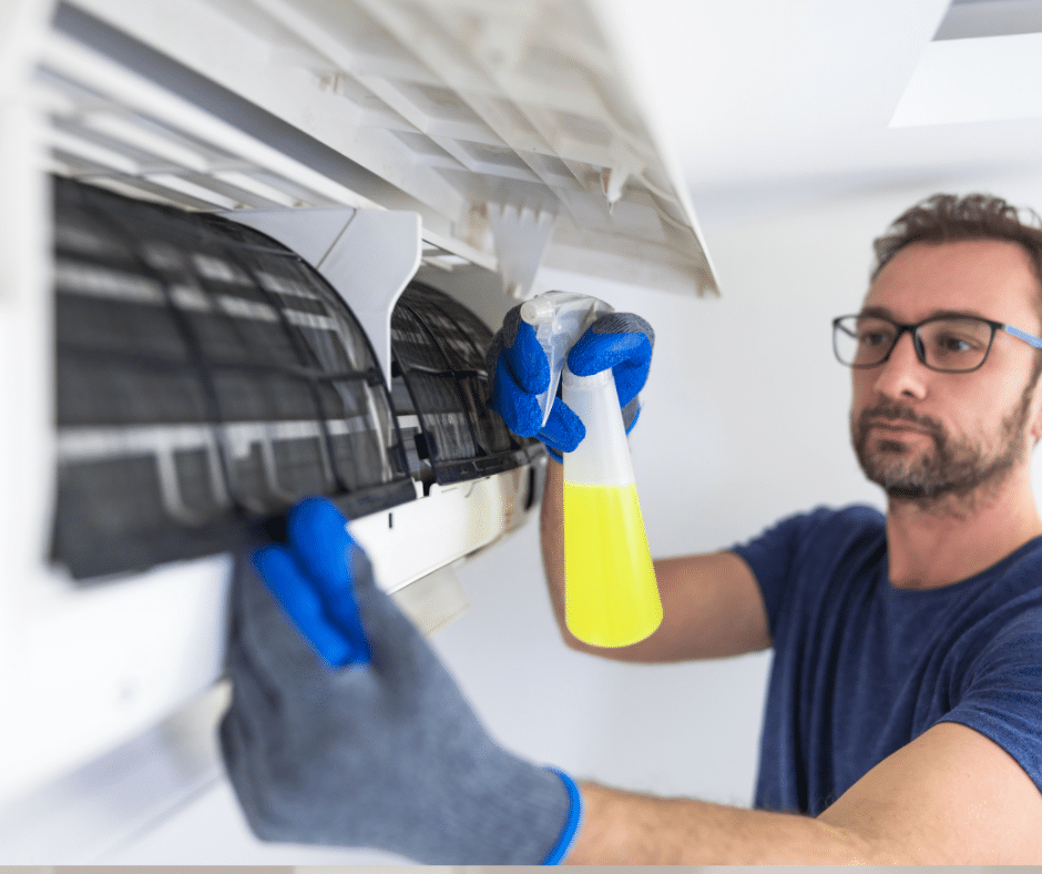 A man removes ice from the inside unit of an AC unit