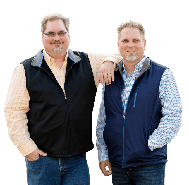 Two men stand side by side, one resting his arm on the other's shoulder, smiling at the camera