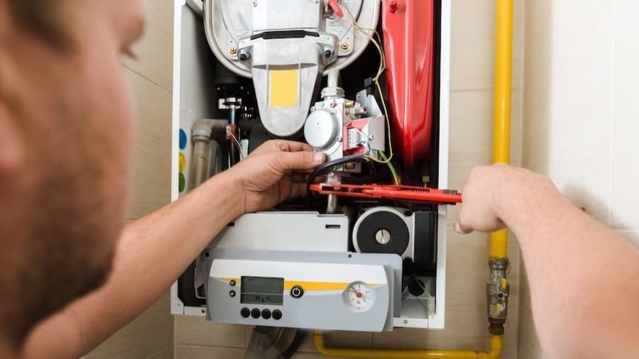 HVAC technician adjusting gas furnace.