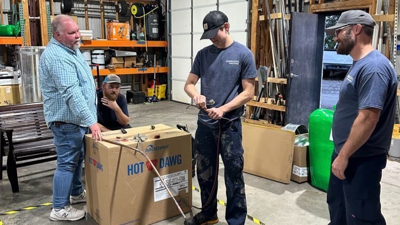 Parker's team standing around geothermal unit in box.