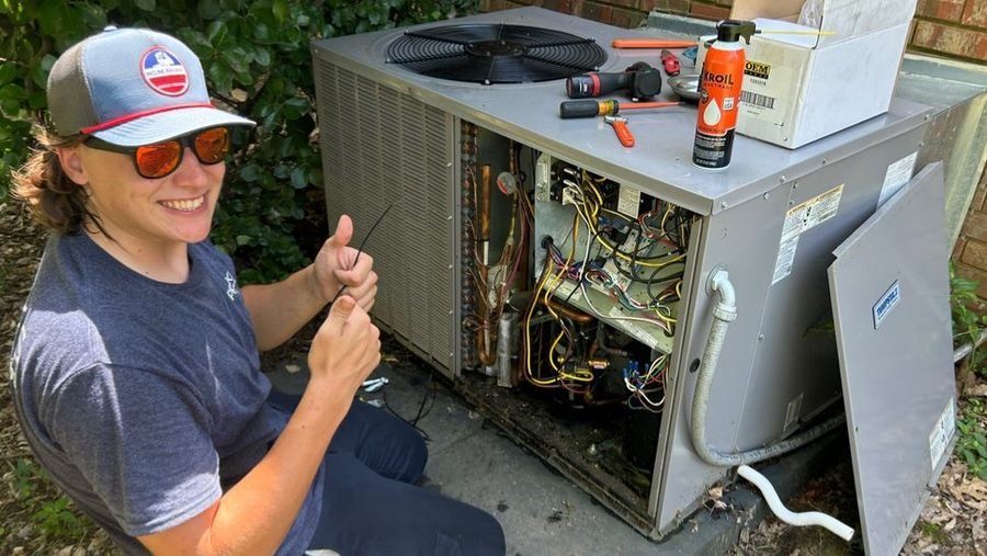Inspecting AC unit for maintenance.